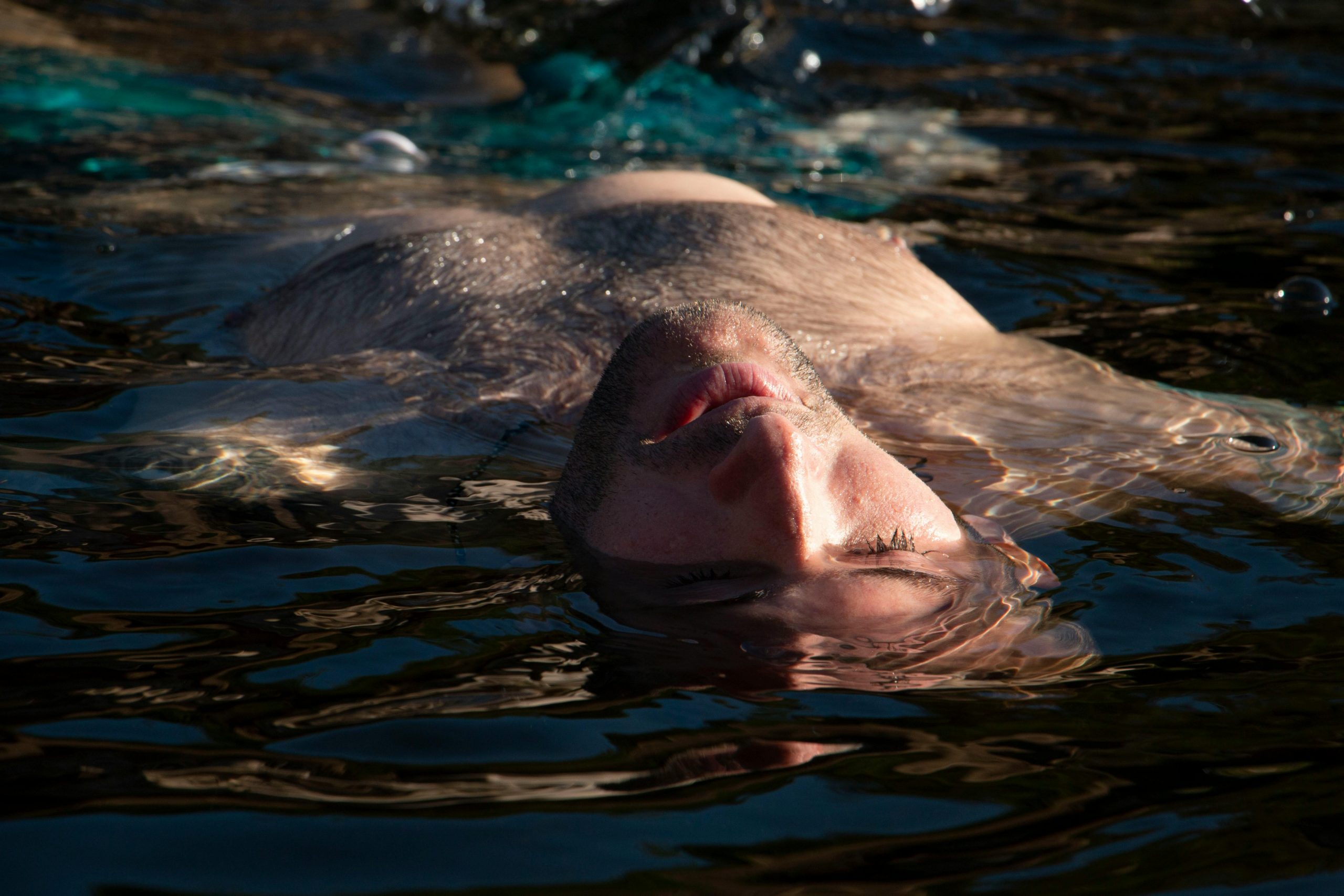 man with eyes closed, floating on water