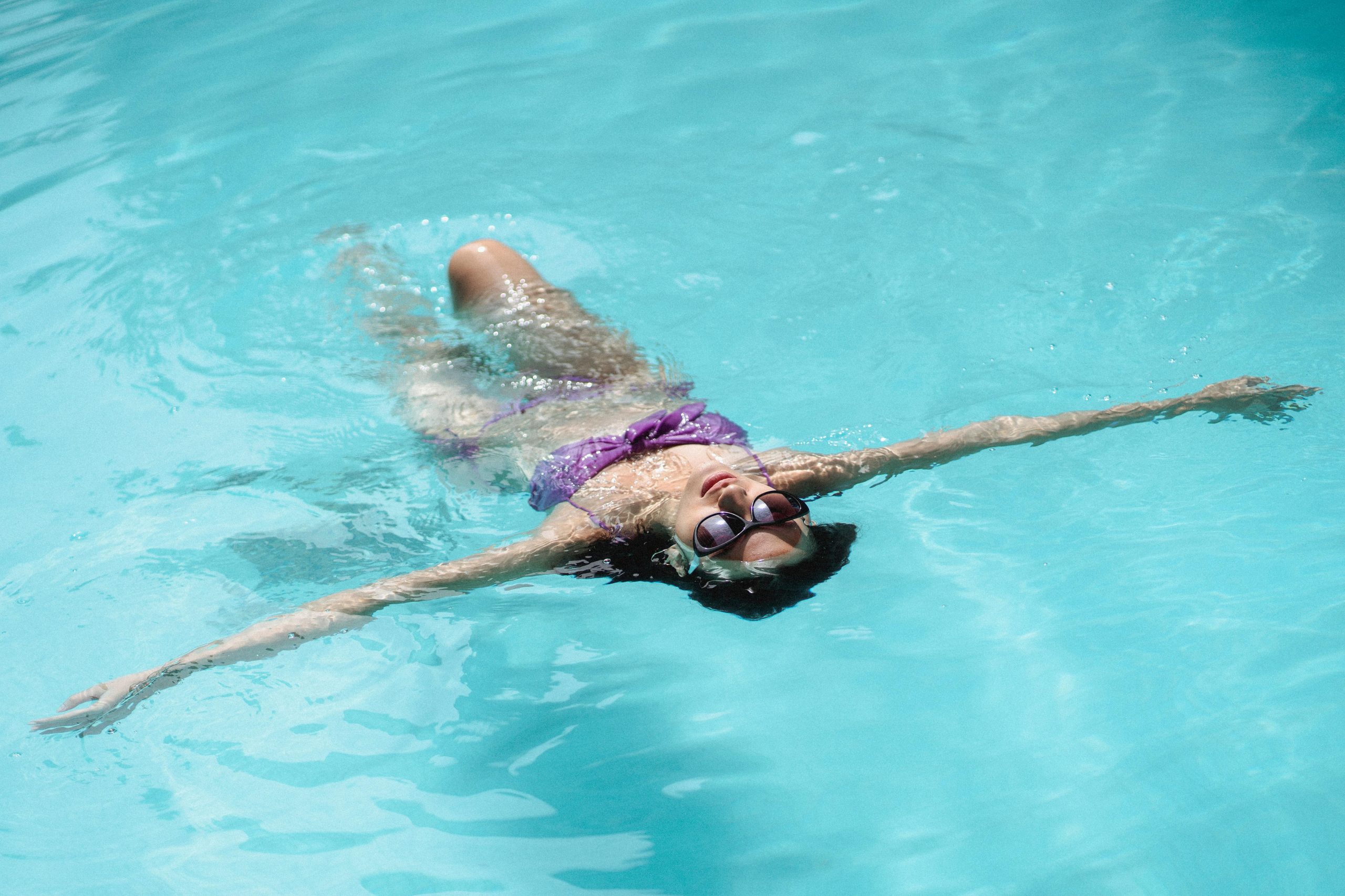 woman in a purple bikini doing a back float in a pool